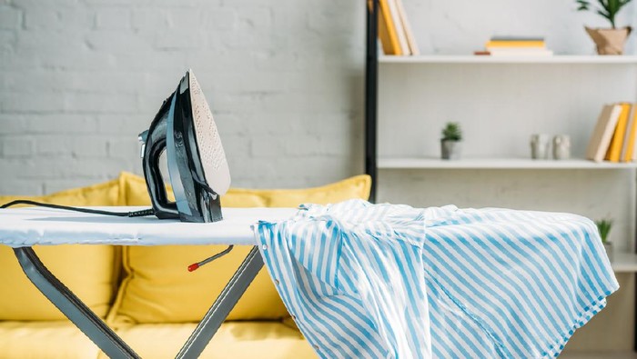 striped blue shirt and iron on ironing board at home