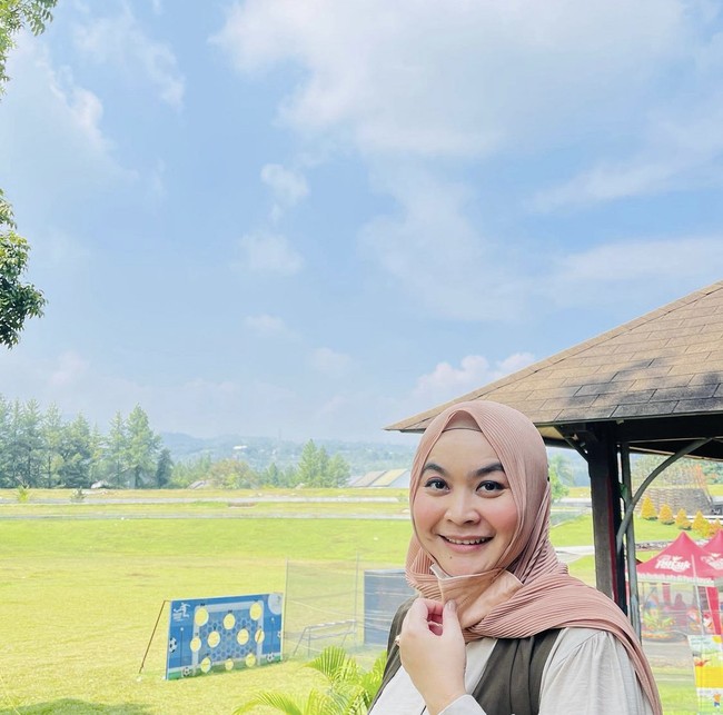 Ulfa Dwiyanti dengan senyumannya yang khas membagikan foto saat memakai hijab plisket. Ia masih terlihat awet muda.  Foto: Dok. Instagram @dwiyanthi_ulfa.