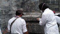 Sambil memegang selang air, Risma yang semula memakai sepatu berganti sandal, dan dengan cekatan menyemprotkan air ke dinding gapura MBK yang baru digosok stafnya.