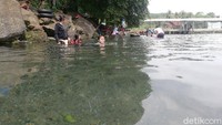 Sebuah mata air yang berasal dari balik bebatuan besar dengan perbukitan di atasnya yang ditumbuhi pohon-pohon besar. (Nur Azis/detikcom)