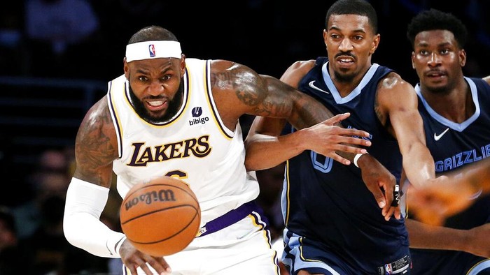 Los Angeles Lakers forward LeBron James, left, and Memphis Grizzlies guard DeAnthony Melton chase the ball during the second half of an NBA basketball game in Los Angeles, Sunday, Oct. 24, 2021. The Lakers won 121-118. (AP Photo/Ringo H.W. Chiu)