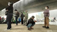 Para pemotor berteduh karena tidak membawa jas hujan.