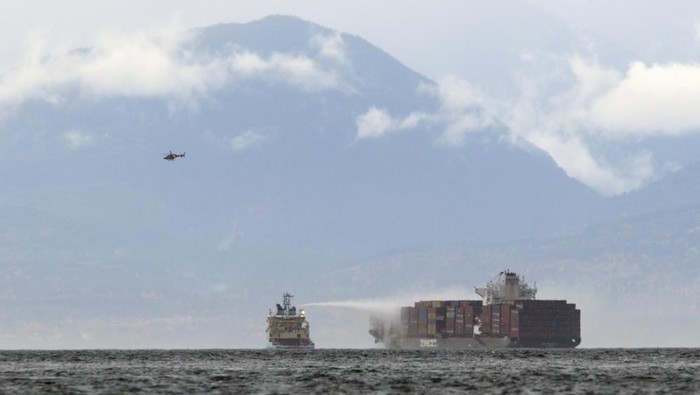 Ships work to control a fire onboard the MV Zim Kingston about eight kilometres from the shore in Victoria, B.C., on Sunday, October 24, 2021. The container ship caught fire on Saturday and 16 crew members were evacuated and brought to Ogden Point Pier. (THE CANADIAN PRESS/Chad Hipolito/The Canadian Press via AP)