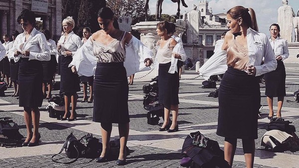 Saat berdiri di atas Bukit Capitolino, pramugari ini menurunkan tas mereka. Kemudian mulai melepas jaket dan seragam Alitalia. (Dok. Instagram/simonaberterame)