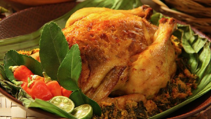 Ayam Betutu, the popular roast chicken dish from Bali. Stuffing of cassava and spices are stuffed inside the chicken. The chicken is garnished with kaffir lime leaves, red chili peppers and lime halves.