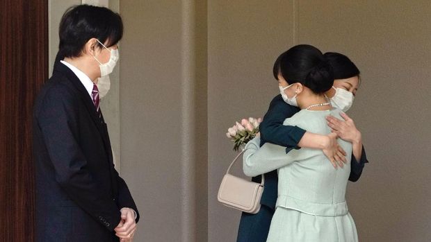 Japan's Princess Mako, right, hugs her sister Princess Kako, watched by her parents Crown Prince Akishino and Crown Princess Kiko, before leaving her home in Akasaka Estate in Tokyo Tuesday, Oct. 26, 2021. Mako and her commoner boyfriend Kei Komuro tied the knot Tuesday without wedding celebration in a marriage that has split the public opinion over her would-be mother-in-law’s financial controversy.  (Koki Sengoku/Kyodo News via AP)