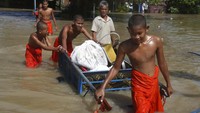 Para biksu mengevakuasi barang-barang melintasi banjir yang merendam pagoda, di luar kota Phom Penh, Kamboja, (26/10/2021). Luapan sungai menyebabkan tempat ibadah mereka di Wat Kampong Kdol terendam banjir.