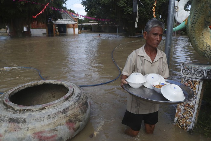 Para biksu mengevakuasi barang-barang melintasi banjir yang merendam pagoda, di luar kota Phon Penh, Kamboja, (26/10/2021). Luapan sungai menyebabkan tempat ibadah mereka di Wat Kampong Kdol terendam banjir.