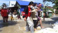 Warga saling bantu melintasi banjir di luar Ibi Kota Pnom Phen, Kamboja.