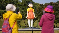 Pengunjung melihat maskot boneka serial Netflix Squid Game di taman Olimpiade, Seoul, Korea Selatan, Selasa (26/10/2021).  