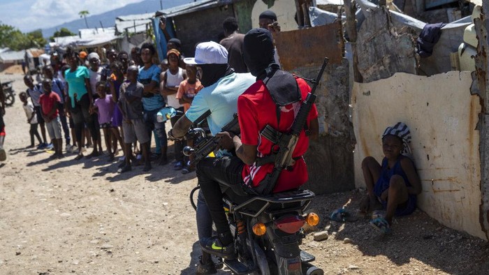G9 coalition gang members ride a motorcycle through the Wharf Jeremy street market in Port-au-Prince, Haiti, Wednesday, Oct. 6, 2021. While some gangs have turned to kidnapping, like those who captured 17 missionaries and their relatives, Jimmy Cherizier, aka Barbecue, a former policeman who leads the G9 gang coalition, has taken control of the port district, gaining a stranglehold on the country's economy. (AP Photo/Rodrigo Abd)