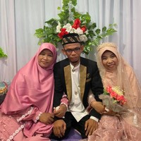 Dalam video tersebut terlihat, istri pertama memakai busana serba pink dan tampil tanpa makeup. Sedangkan istri kedua yang hari itu menjadi pengantin, mengenakan gaun dan veil wedding warna coral. Dan sang suami menggunakan jas serta peci hitam. Foto: Dok. Facebook Nana Ratnawati Palaha.