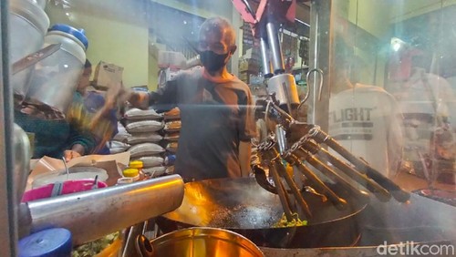 Dartadi (60) memasak nasi goreng dengan cara berbeda. Ia dibantu alat atau robot saat mengolah nasi di atas wajan.