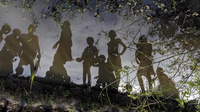 Perubahan Iklim Ancam Mata Pencarian Ribuan Warga Sudan Children standing on a small mud dyke are reflected in the stagnant water, in Langic, Northern Bahr el Ghazal State, South Sudan, Wednesday, Oct. 20, 2021. This is the third straight year of extreme flooding in South Sudan, further imperiling livelihoods in the world's youngest country. A five-year civil war, hunger and corruption have all challenged the nation. Now climate change, which the United Nations has blamed on the flooding, is impossible to ignore.(AP Photo/Adrienne Surprenant)
