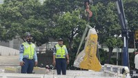 Alat berat mengangkat separator busway yang telah hancur.