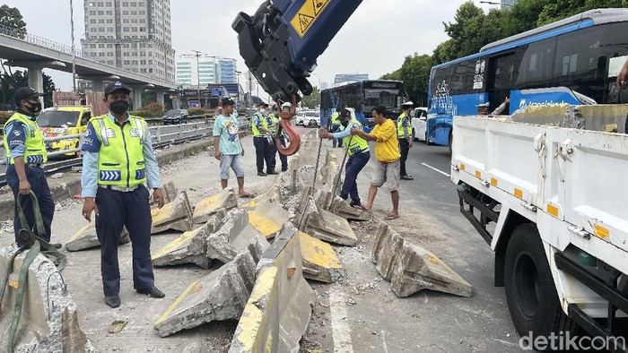 Sejumlah petugas dari Dinas Perhubungan DKI Jakarta, melakukan evakuasi separator busway yang hancur berserakan akibat ditabrak truk muatan tanah, di Jalan MT Haryono, Cawang, Jakarta Timur, Rabu (27/10/2021).