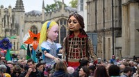 Little Amal melintasi berbagai negara di Eropa sejauh 8.000 kilometer dan tahun ini menandai peringatan 150 tahun Through the Looking-Glass karya Lewis Carroll dengan menciptakan boneka Alice raksasa.  Foto: Getty Images/Leon Neal