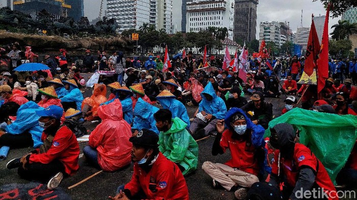 Massa Gerakan Buruh Bersama Rakyat (Gebrak) berdemonstrasi memkritik Jokowi di depan Patung Kuda, Jakarta, Kamis (28/10). Mereka berorasi di bawah rintik hujan.