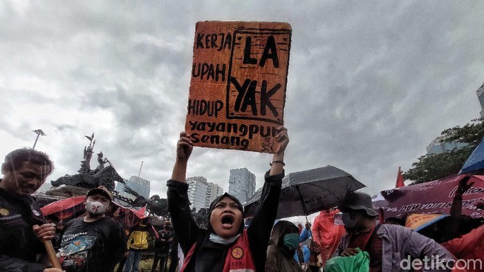 Massa Gerakan Buruh Bersama Rakyat (Gebrak) berdemonstrasi memkritik Jokowi di depan Patung Kuda, Jakarta, Kamis (28/10). Mereka berorasi di bawah rintik hujan.