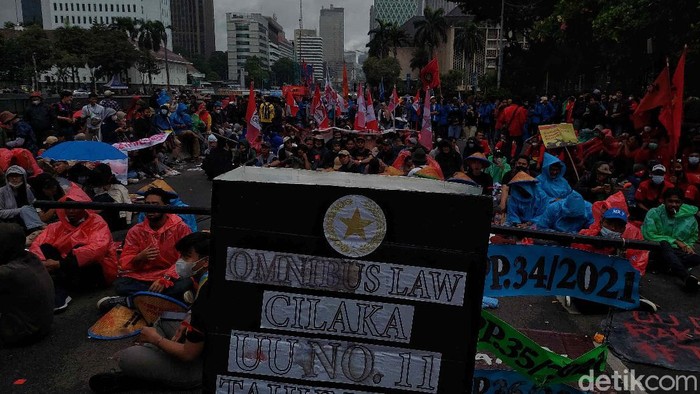 Massa Gerakan Buruh Bersama Rakyat (Gebrak) berdemonstrasi memkritik Jokowi di depan Patung Kuda, Jakarta, Kamis (28/10). Mereka berorasi di bawah rintik hujan.