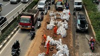 Tumpahan tanah langsung dimasukkan ke dalam karung oleh para petugas yang kemudian dimasukkan kembali ke dalam truk untuk diangkut agar jalan kembali bersih dan bisa dilalui kembali oleh kendaraan yang melintas.