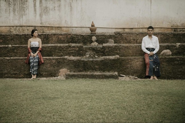Ide foto prewedding tanpa bersentuhan yang terakhir ini bisa kamu terapkan. Memakai busana yang seragam dan tanpa alas kaki, dilengkapi dengan kain tradisional yang cantik. Foto: Dok. Instagram @ceritatentangsenja.