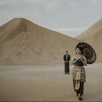 Foto prewedding di Gurun Pasir Desa Busung, Kepulauan Riau ini juga bisa menjadi inspirasi kamu. Sepasang calon pengantin mengenakan busana adat dilengkapi dengan payung tradisional yang cantik. Sosok pria seolah berjarak sambil memandang wanitanya yang ada di depan. Foto: Dok. Instagram @ceritatentangsenja.