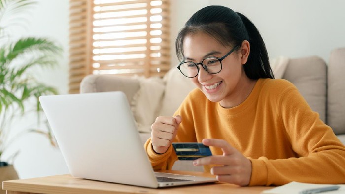 beautiful young woman are buying online with a credit card while sitting in the living room morning. Women are using a computer laptop and doing online transactions at home