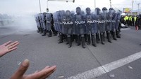 Polisi membentuk barikade untuk menghadapi aksi yang menolak kenaikan harga bahan bakar, di Saquisili, Selasa (26/10). Puluhan pendemo dilaporkan ditahan dalam aksi tersebut.