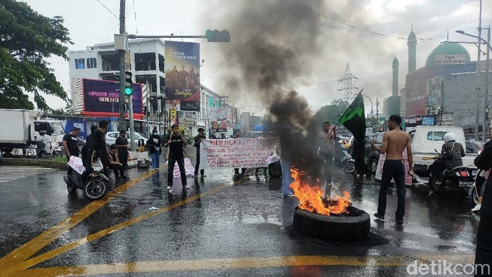 Mahasiswa di Makassar membakar ban di depan pos polantas di lampu merah pertigaan Tello saat unjuk rasa di hari Sumpah Pemuda. (Ibnu Munsir/detikcom)