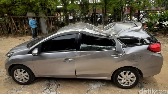 Sebuah mobil tertimpa pohon kering di jalanan Pekanbaru, Riau. Akibat kejadian tersebut bagian tengah mobil tampak ringsek.
