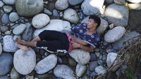 Seorang migran tampak beristirahat di antara bebatuan di tengah perjalanannya menuju Amerika Serikat. 