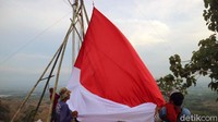 Pengibaran bendera merah putih raksana melibatkan pemuda dan warga setempat.