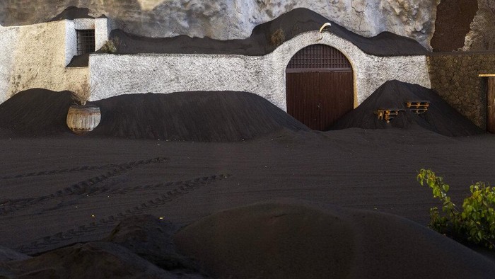 A street is covered with ash from a volcano as it continues to erupt in Las Manchas de Abajo on the Canary island of La Palma, Spain, Wednesday, Oct. 27, 2021. Residents on Spain's La Palma island braced Wednesday for the possibility of bigger earthquakes that could compound the damage from a volcano spilling lava more than five weeks since it erupted. (AP Photo/Emilio Morenatti)