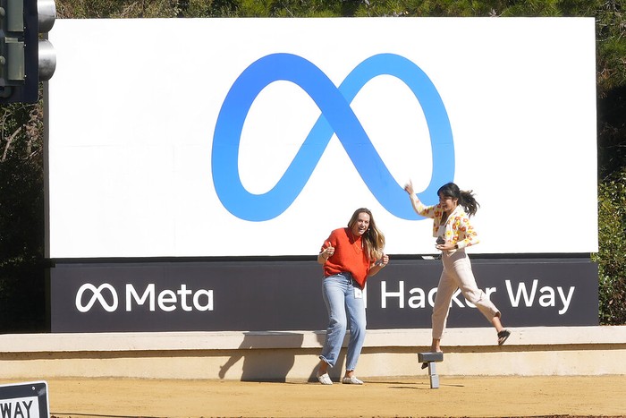 Facebook employees take a photo with the companys new name and logo outside its headquarters in Menlo Park, Calif., Thursday, Oct. 28, 2021, after the company announced that it is changing its name to Meta Platforms Inc. (AP Photo/Tony Avelar)