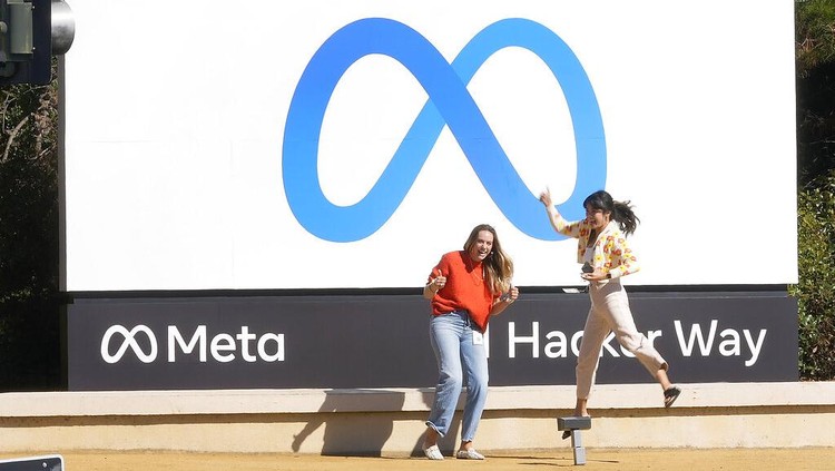 Facebook employees take a photo with the companys new name and logo outside its headquarters in Menlo Park, Calif., Thursday, Oct. 28, 2021, after the company announced that it is changing its name to Meta Platforms Inc. (AP Photo/Tony Avelar)