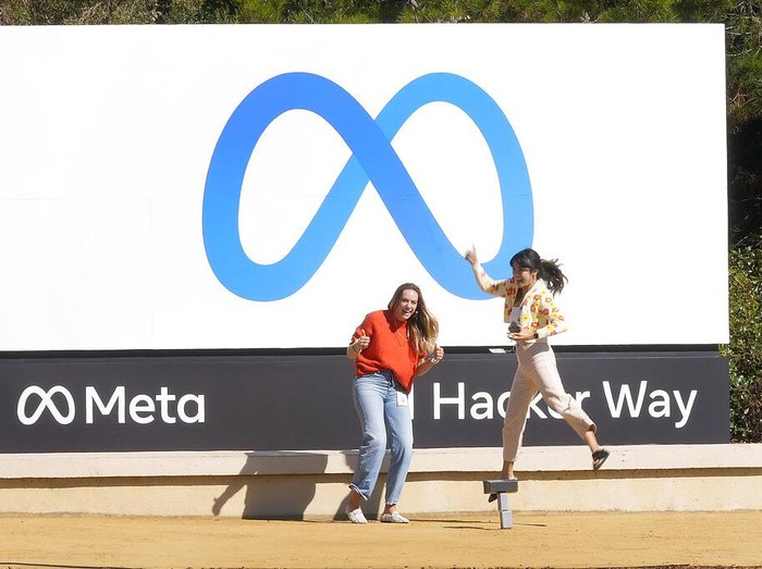 Facebook employees take a photo with the companys new name and logo outside its headquarters in Menlo Park, Calif., Thursday, Oct. 28, 2021, after the company announced that it is changing its name to Meta Platforms Inc. (AP Photo/Tony Avelar)
