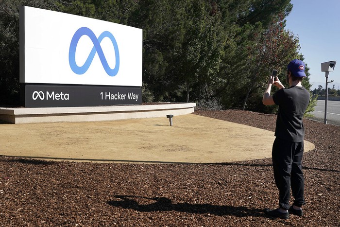 Facebook employees take a photo with the companys new name and logo outside its headquarters in Menlo Park, Calif., Thursday, Oct. 28, 2021, after the company announced that it is changing its name to Meta Platforms Inc. (AP Photo/Tony Avelar)