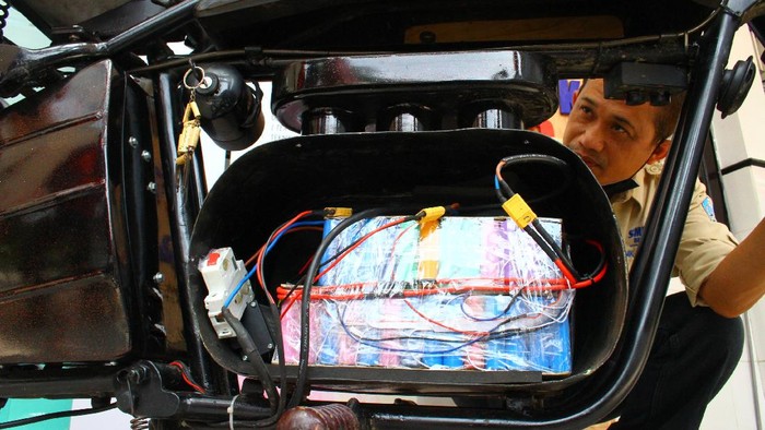 Kepala Sekolah Cone Kustarto (kanan) menunjukkan cara kerja purwarupa sepeda motor listrik hasil inovasinya di SMKN 5 Malang, Jawa Timur, Jumat (29/10/2021). Sepeda motor listrik tesebut dirakit dengan memanfaatkan baterai komputer jinjing bekas dan mampu melaju dengan kecepatan 70 kilometer per jam dengan lama pengisian ulang hanya selama 2 jam saja. ANTARA FOTO/Ari Bowo Sucipto/hp.