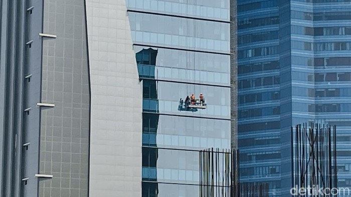Di musim hujan, pekerja pembersih kaca atau yang dikenal gondola man harus ekstra kerja membersihkan kaca-kaca gedung pencakar langit.