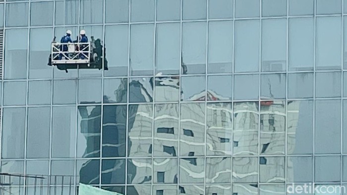 Di musim hujan, pekerja pembersih kaca atau yang dikenal gondola man harus ekstra kerja membersihkan kaca-kaca gedung pencakar langit.