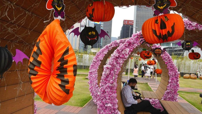 Semarak Halloween Hiasi Taman di Hong Kong People wearing face masks to prevent the spread of coronavirus, walk past Halloween decorations at a park in Hong Kong, Wednesday, Oct. 27, 2021. (AP Photo/Vincent Yu)