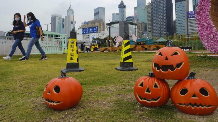 People wearing face masks to prevent the spread of coronavirus, walk past Halloween decorations at a park in Hong Kong, Wednesday, Oct. 27, 2021. (AP Photo/Vincent Yu)