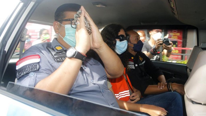 Heather Mack of Chicago, Ill., right, is escorted by Indonesian immigration officers at Immigration detention center in Jimbaran, Bali, Indonesia on Friday, Oct. 29, 2021. The American woman convicted of helping to kill her mother on Indonesia's tourist island of Bali in 2014 walked free from prison Friday after serving seven years of a 10-year sentence and will be deported to the United States. (AP Photo/Firdia Lisnawati)
