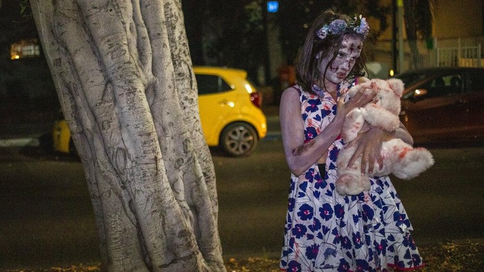 A girl wears zombie make-up and outfit as she participates in the Zombie Walk 2021, part of Halloween weekend in Tel Aviv, Israel, Saturday, Oct. 30, 2021. (AP Photo/Ariel Schalit)