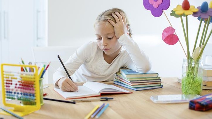 Little girl is engaged remotely with a teacher via video communication in her room