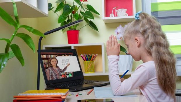 Little girl is engaged remotely with a teacher via video communication in her room
