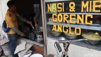 Satu orang berperan menggowes roda yang ditempelkan dekat anglo pakai tangan, satu orang berperan memasukkan bumbu dan makanan yang akan digoreng. Sedangkan satu orang berperan untuk memegang spatula untuk meratakan bambu masakan. Foto: detikcom/Wisma Putra