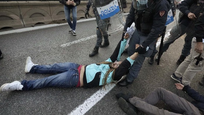 Sibuknya Polisi Italia Tangani Pendemo KTT G20 Italian Police remove climate activists trying to block traffic in front of the Italian Ministry of the Ecological Transition in Rome's via Cristoforo Colombo, one of the main road leading to La Nuvola (the cloud) convention center where the G20 summit is taking place, Saturday, Oct. 30, 2021. (AP Photo/Luca Bruno)