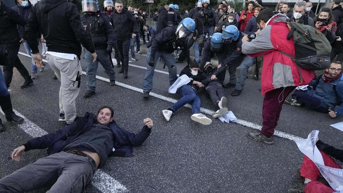 Italian Police remove climate activists trying to block traffic in front of the Italian Ministry of the Ecological Transition in Rome's via Cristoforo Colombo, one of the main road leading to La Nuvola (the cloud) convention center where the G20 summit is taking place, Saturday, Oct. 30, 2021. (AP Photo/Luca Bruno)